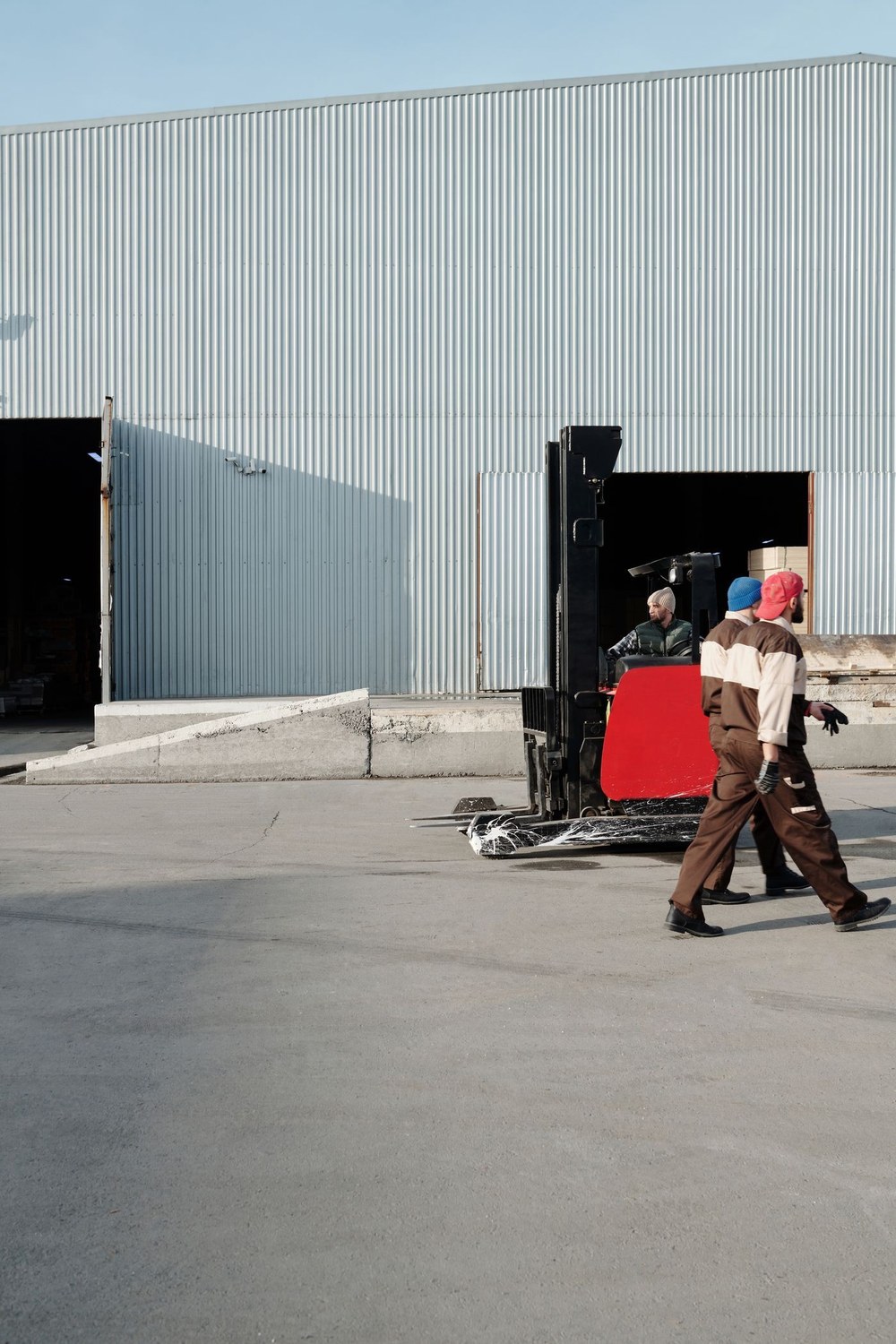 Warehouse workers beside a forklift and stacked goods